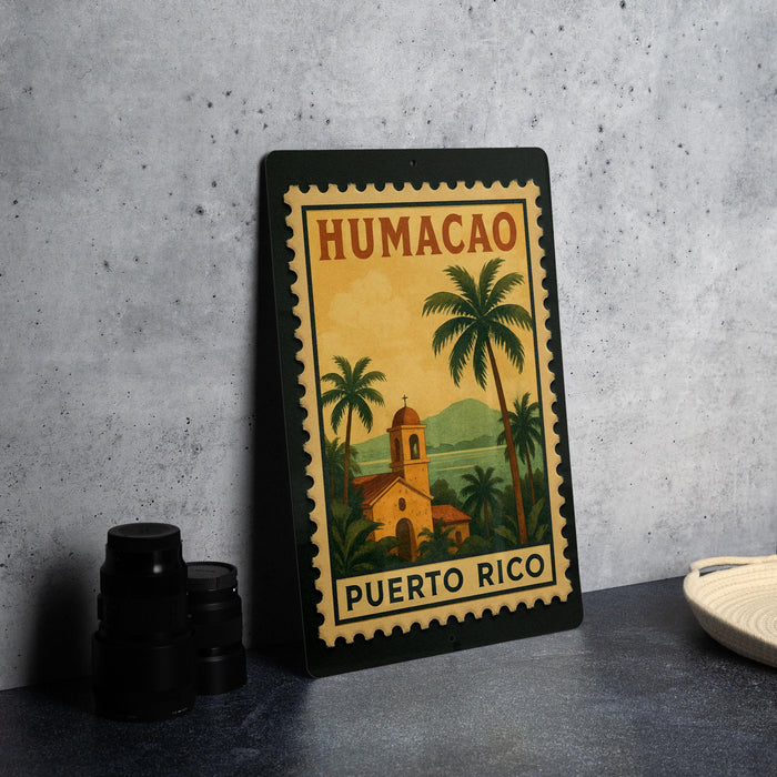 A framed poster of Humacao, the capital of Puerto Rico, featuring a tropical landscape with palm trees and a church.