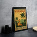 A framed poster of Humacao, the capital of Puerto Rico, featuring a tropical landscape with palm trees and a church.