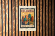 A metal sign with a colorful illustration of a city skyline and the text "COLUMBIA SOUTH CAROLINA" is displayed on a wooden wall.