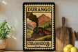 A framed vintage-style stamp depicting a steam locomotive on a train traveling through a mountainous landscape, with the text "DURANGO COLORADO 8c U.S."