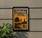 A vintage-style postage stamp from Texas, featuring a silhouette of a town and a water tower, mounted on a wall.