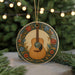 A decorative ornament featuring a guitar is displayed on a table, surrounded by pine branches and twinkling lights.