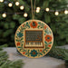 A decorative ornament featuring a piano keyboard and flowers, hanging from a string against a blurred background of greenery and lights.