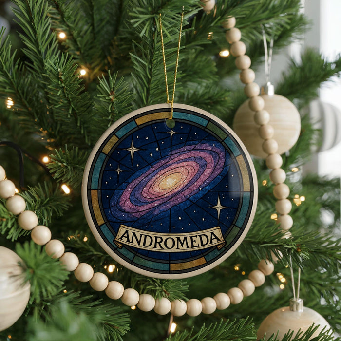 A Christmas tree decorated with ornaments, including a circular ornament with a colorful galaxy design and the word "ANDROMEDA" written on it.