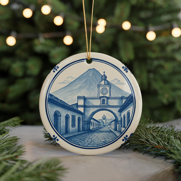 A decorative ceramic ornament featuring a detailed illustration of a town with a clock tower, set against a backdrop of a mountain and a bridge.