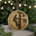 A circular ornament featuring a silhouette of a person climbing a tree, with a blurred background of Christmas lights.