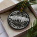A black and white ornament with the word "ARCHIVIST" written on it, placed inside a box with pine branches.