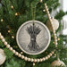 A Christmas tree decorated with ornaments, including a circular ornament with a black and white illustration of arrows and a wooden bead garland.