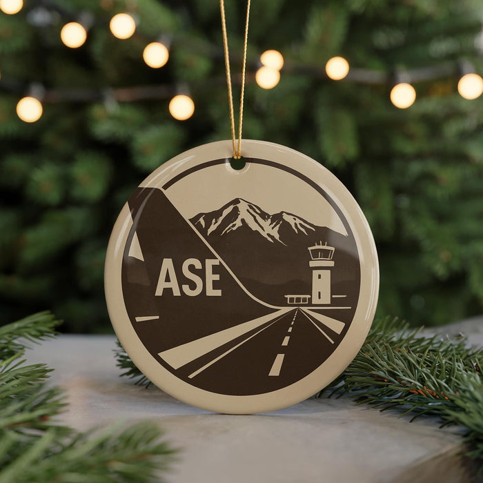 A circular ornament with a graphic design featuring a mountain range and a control tower, with the word "ASE" prominently displayed.