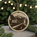 A circular ornament with a graphic design featuring a mountain range and a control tower, with the word "ASE" prominently displayed.