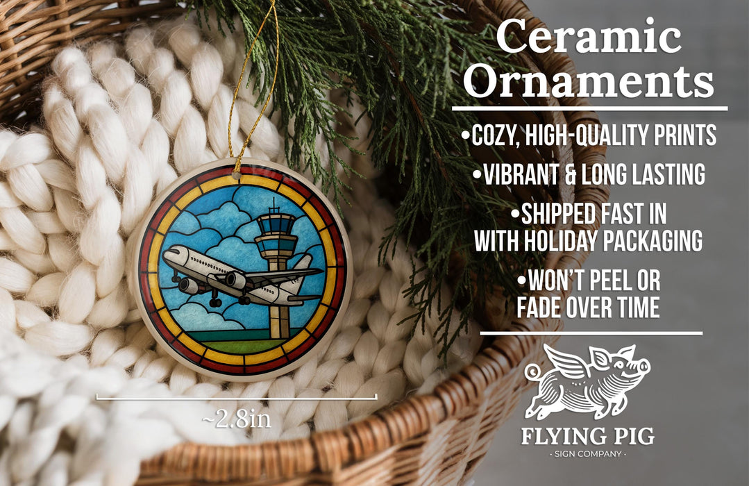 Ceramic ornaments, featuring a stained glass-style design of an airplane, are displayed in a basket with pine branches.