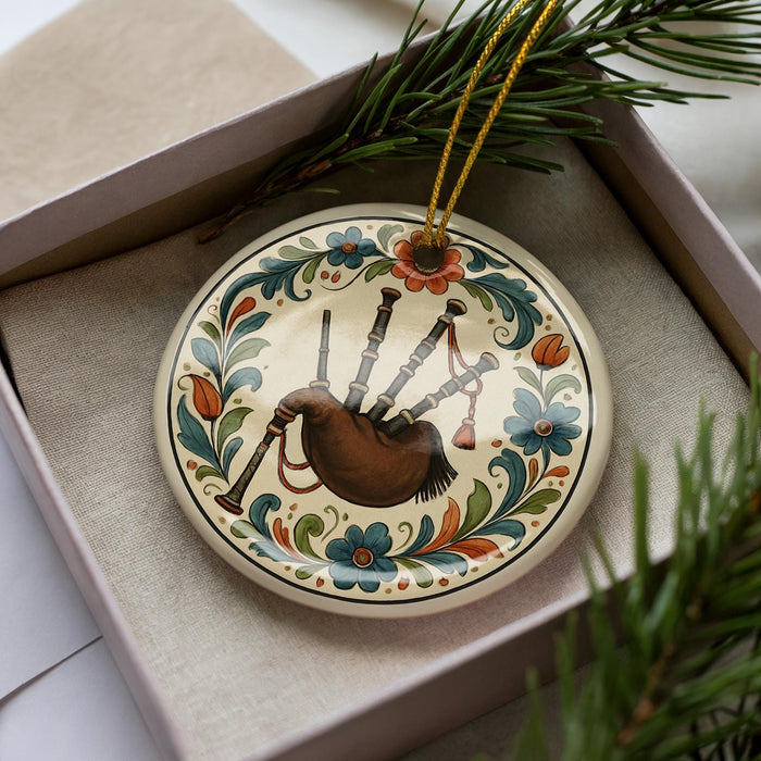 A decorative ornament in a box, featuring a piper blowing a bagpipe.