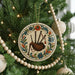 A Christmas tree decorated with ornaments, including a circular ornament featuring a bagpiper and a beaded garland.