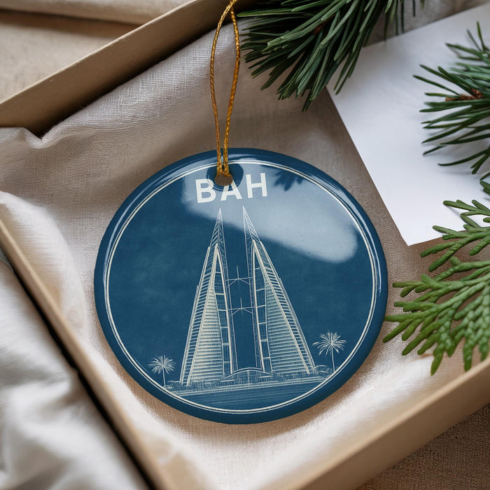 A blue circular ornament with a white illustration of a tall building, hanging from a string.