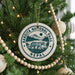 A round ornament on a Christmas tree, featuring a tiger and the text "Bardiya National Park Nepal".