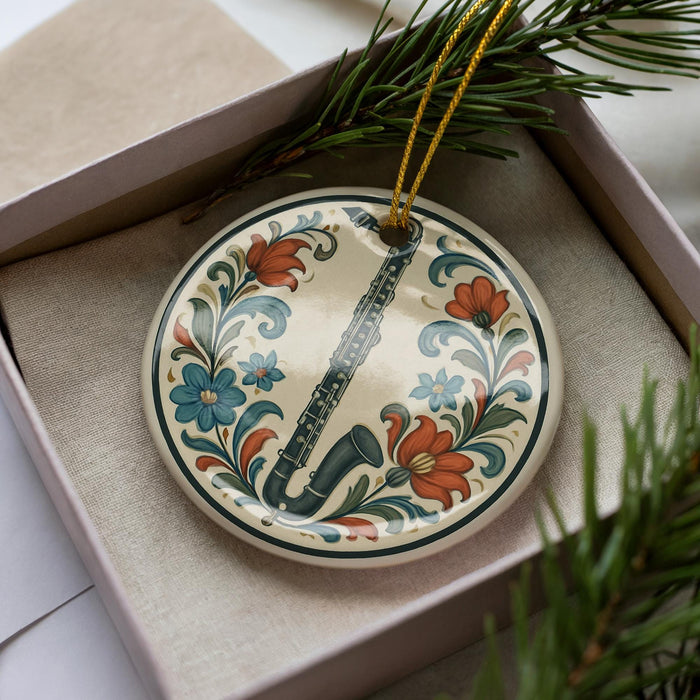 A decorative ornament in a box, featuring a saxophone surrounded by colorful floral designs.