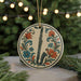 A decorative ornament featuring a saxophone surrounded by flowers and leaves, hanging from a string.