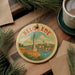 A round ornament with a picture of Belgrade, the capital city of Bulgaria, is displayed on a wooden surface.