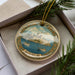 A decorative ornament in a box, featuring a painting of Bodrum, a city in Turkey.