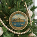 A circular ornament on a Christmas tree, featuring a castle and boats in the background.