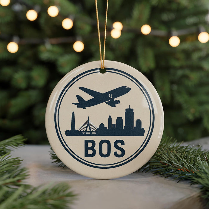 A circular ornament with a silhouette of a city skyline and an airplane, along with the text "BOS" (Boston, Ohio) on it, is displayed on a Christmas tree.