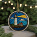 A stained glass ornament depicting a lighthouse on a beach, with a bright sun shining through the windows, is displayed in front of a Christmas tree with twinkling lights.