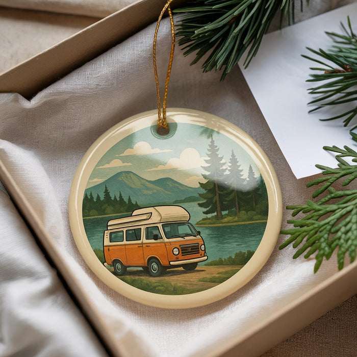 A round ornament featuring an orange van on a road, with a scenic mountain landscape in the background.