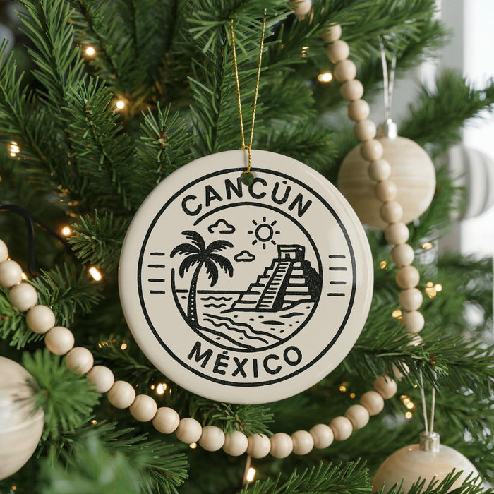 A Christmas tree decorated with ornaments, including a circular ornament with the text "CANCUN MEXICO" and a palm tree design.