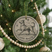 A Christmas tree decorated with ornaments, including a circular ornament with a dog and stars, and a string of wooden beads.