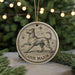 A circular ornament featuring a dog and stars, with the text "Canis Major" below it, is displayed on a table with pine branches in the background.