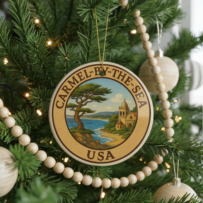 A Christmas tree decorated with ornaments, including a circular ornament with a scenic image of a coastal town and the text "Carmel-by-the-Sea USA".