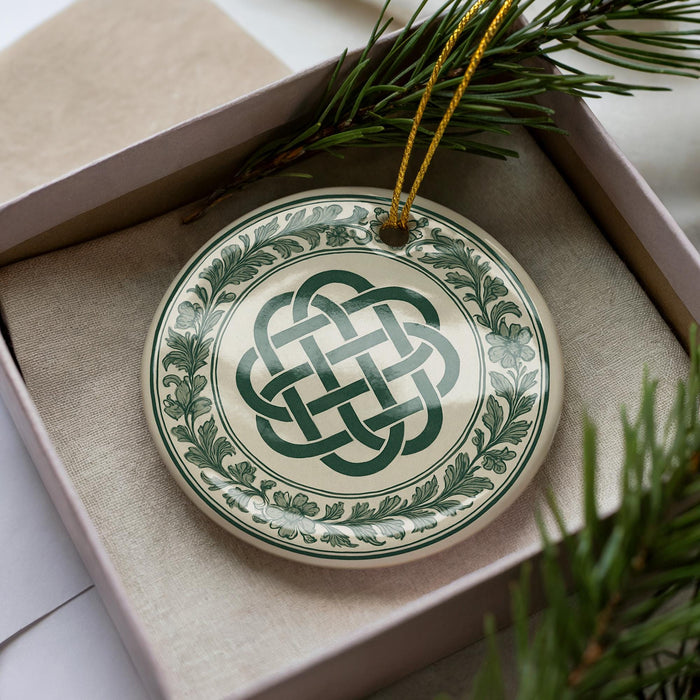 A decorative ornament in a box, featuring a circular design with a green and white color scheme and a Celtic knot pattern.