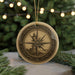 A decorative compass ornament with a lighthouse on a Christmas tree, surrounded by pine branches and twinkling lights.