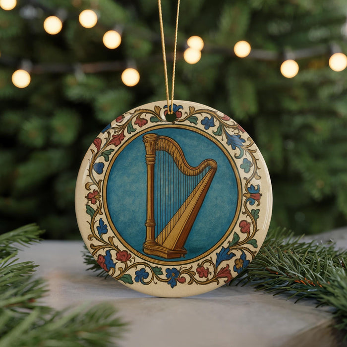 A decorative ornament featuring a harp is displayed on a table, surrounded by pine branches and twinkling lights.