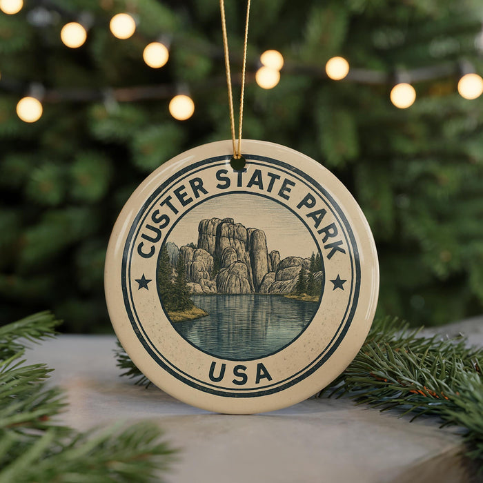 A circular ornament with the text "CUSTER STATE PARK USA" and an illustration of a mountain landscape, hanging from a string.