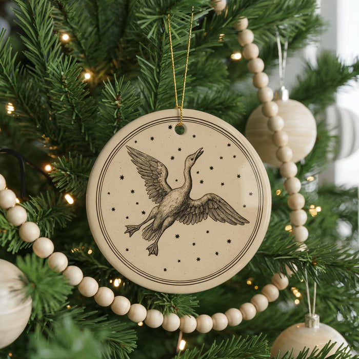 A Christmas tree decorated with ornaments, including a circular ornament with a bird illustration and a string of wooden beads.