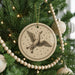 A Christmas tree decorated with ornaments, including a circular ornament with a bird illustration and a string of wooden beads.