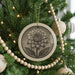 A Christmas tree decorated with ornaments, including a large circular ornament with a detailed flower design.