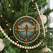 A decorative ornament featuring a dragonfly is hanging on a Christmas tree, surrounded by lights and ornaments.