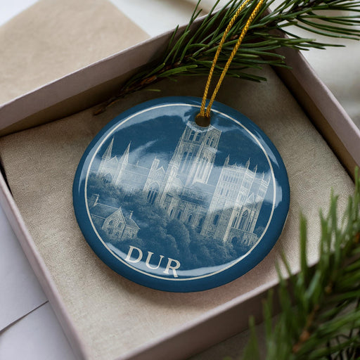 A blue ornament with a picture of a cathedral on it, hanging from a string.
