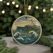 A round ornament featuring a lighthouse on a cliff, with waves crashing against the shore in the background.