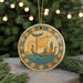 A decorative ornament featuring a sailing ship with a winged figure, surrounded by symbols and designs, is displayed on a Christmas tree.
