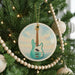A Christmas tree decorated with ornaments, including a circular ornament featuring a guitar and a string of beads.