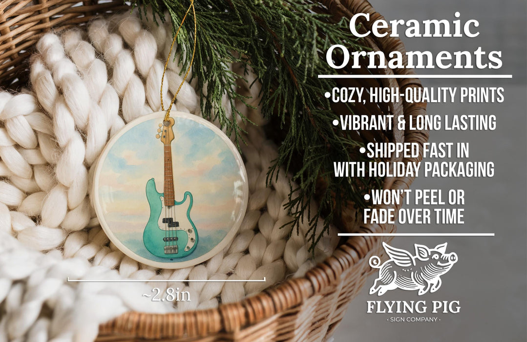 Ceramic ornaments, featuring a blue guitar, are displayed in a basket with a pine branch.