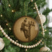 A round ornament on a Christmas tree featuring a man working on a telephone pole.