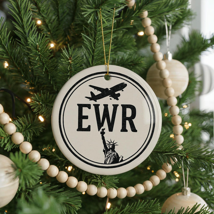 A Christmas tree decorated with ornaments, including a circular ornament with the letters "EWR" and a silhouette of the Statue of Liberty.