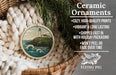 Ceramic ornaments, featuring a lighthouse on a cliff, are displayed in a basket with a pine branch.