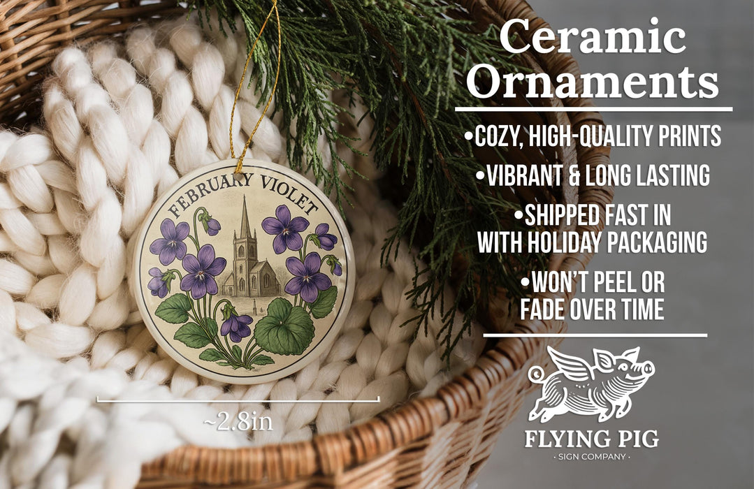 Ceramic ornaments, specifically a February Violet ornament, are displayed in a woven basket. The ornament features purple flowers and a church spire. The text highlights the ornament's features, such as being cozy, high-quality, vibrant, and long-lasting, and mentions that it is shipped fast in holiday packaging, won't peel, and fades over time. The image also includes a scale for size comparison and the logo of a company called "Flying Pig - SIGN COMPANY".