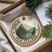A circular ornament with the text "FIORDLAND NATIONAL PARK NEW ZEALAND" printed on it, surrounded by a scenic mountain landscape.