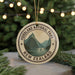 A circular ornament with the text "FIORDLAND NATIONAL PARK NEW ZEALAND" and a mountain landscape design, hanging from a string.